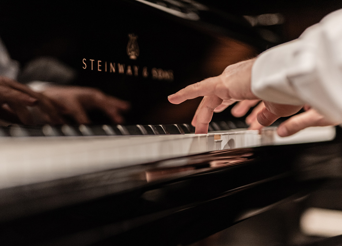 Dłoń pianisty na klawiaturze fortepianu.