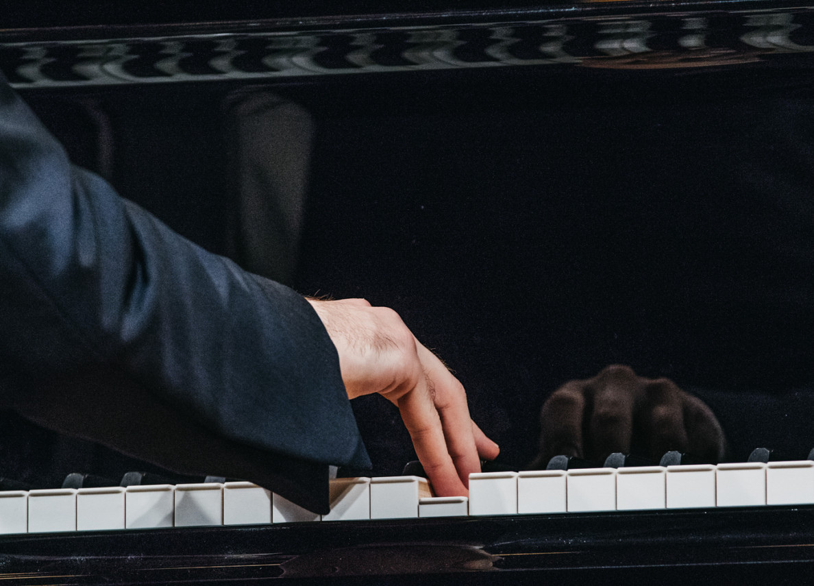 Dłoń pianisty na klawiaturze fortepianu.